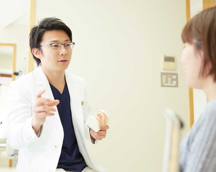 矯正治療の流れを説明してる男性歯科医師