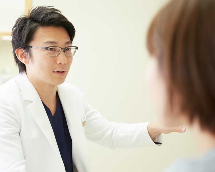 診断結果を女性に伝えている男性歯科医師